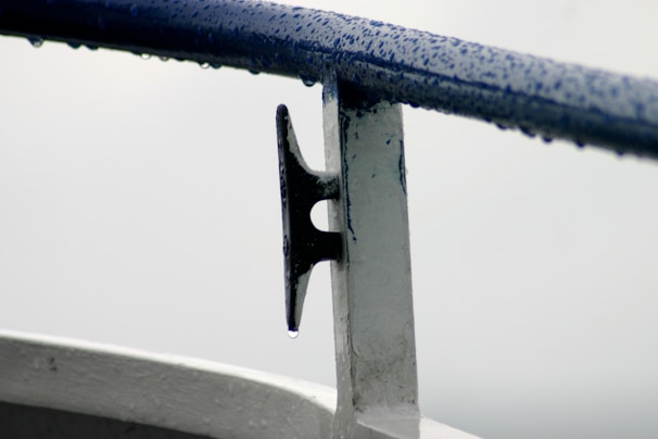 Close-up of stainless steel marine bolts and screws glistening with seawater droplets on a boat deck.