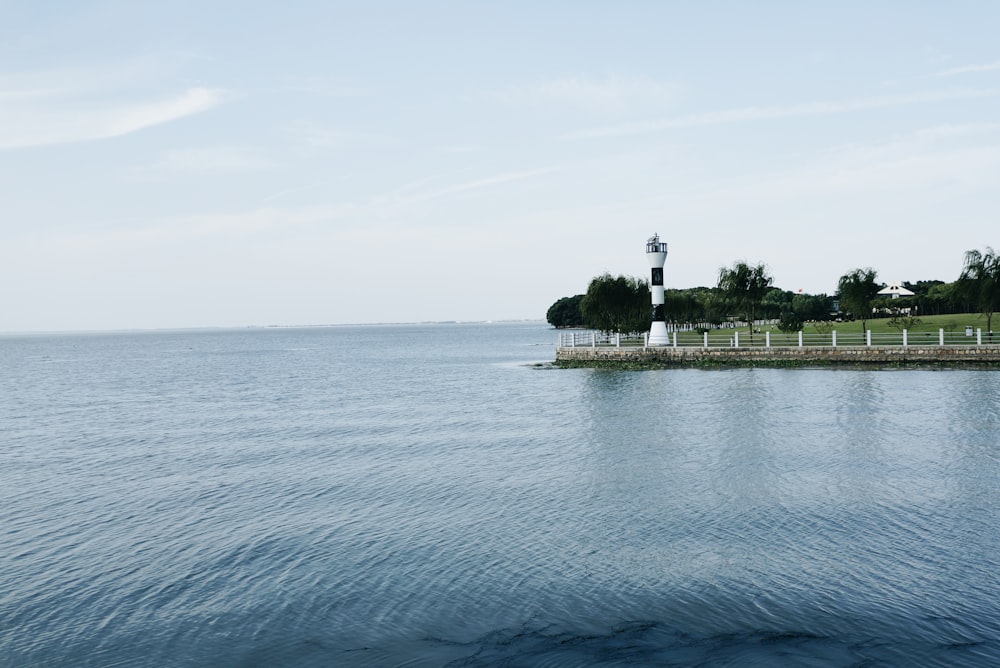 Weißer und schwarzer Leuchtturm neben dem blauen Ozean während des Tages