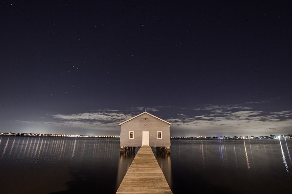 white and gray wooden house in the middle of body of water