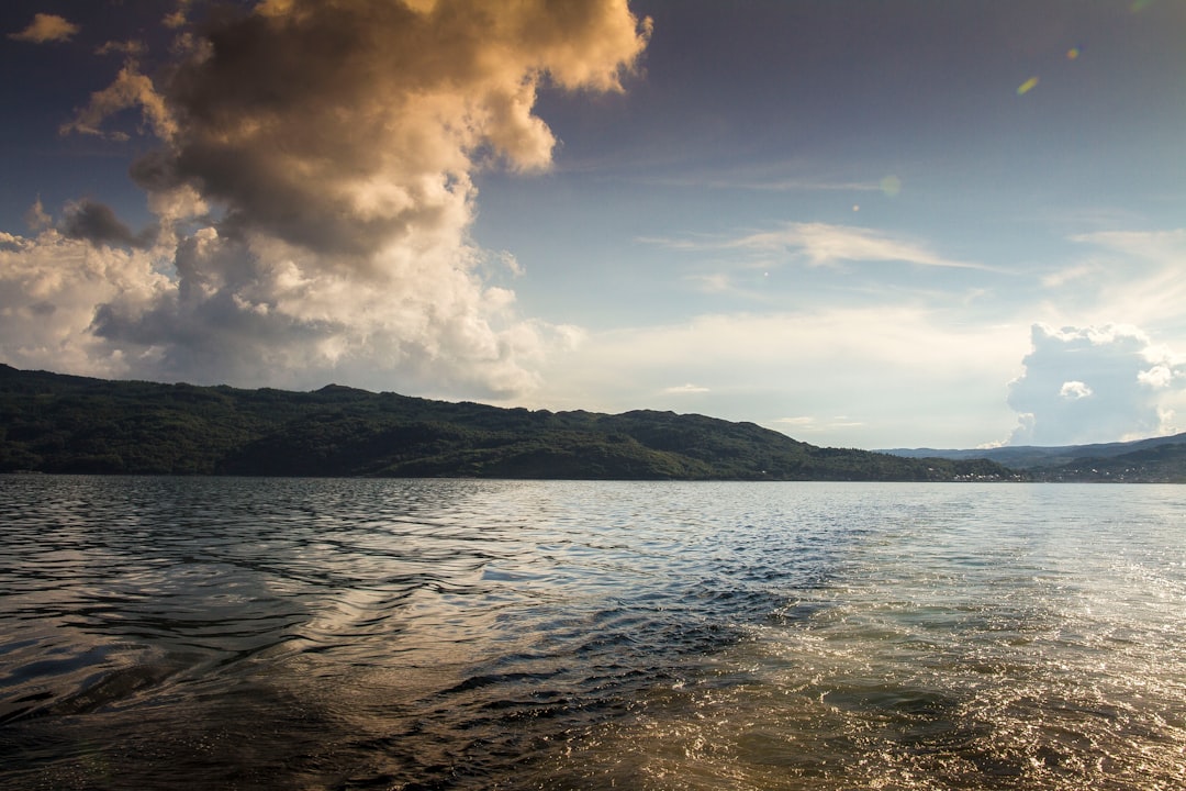 calm body of water with cloudy skies