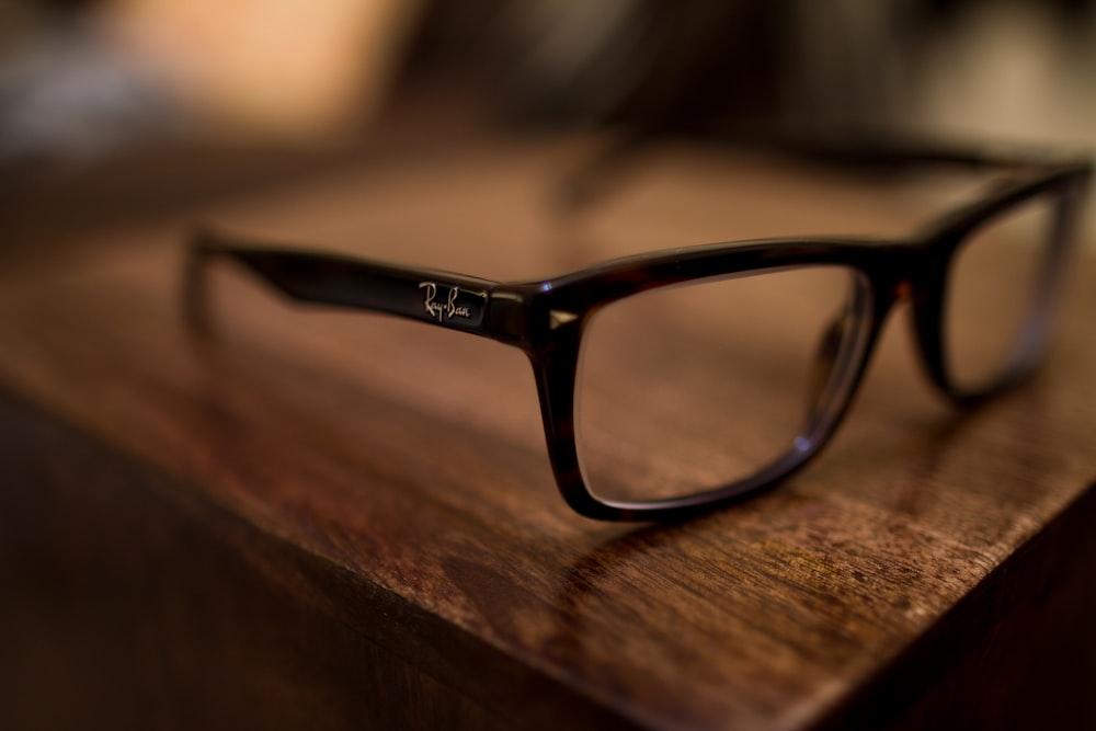 occhiali da vista con montatura nera su tavolo marrone