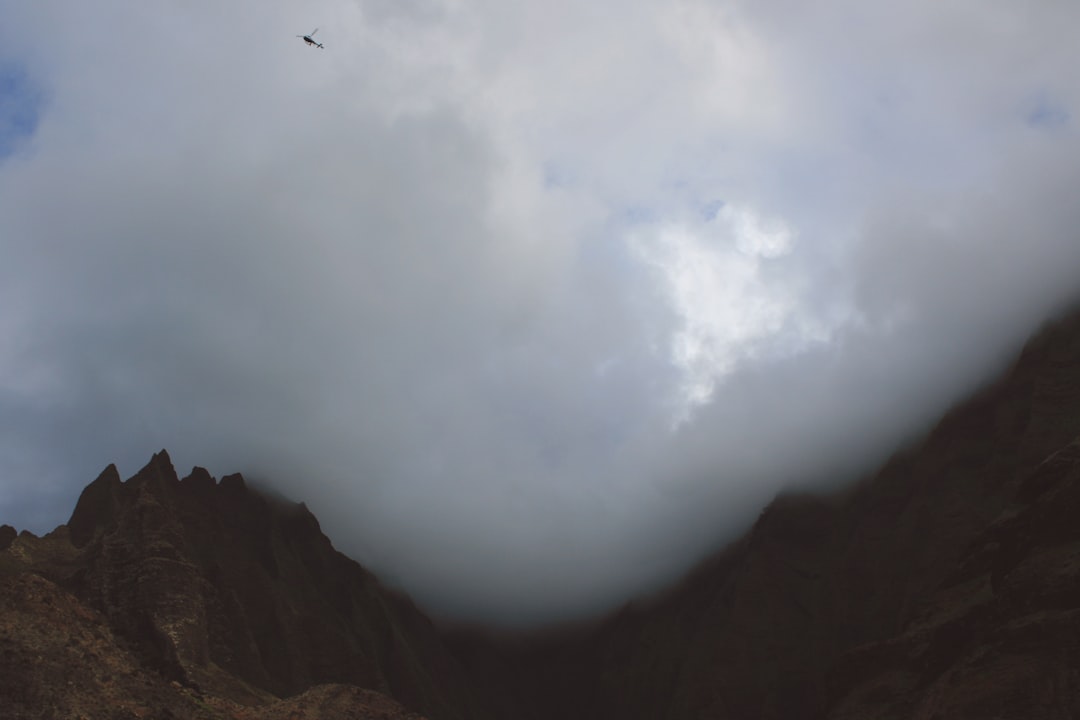 A helicopter flies through billowing clouds over a mountain landscape