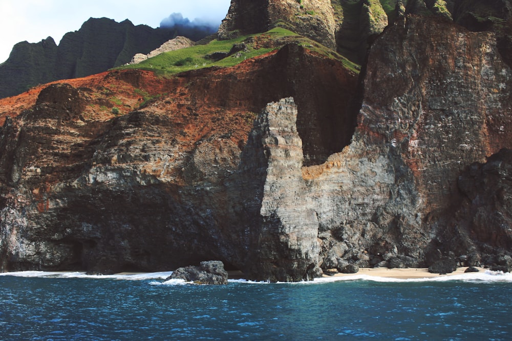 brown rock formation beside body of water