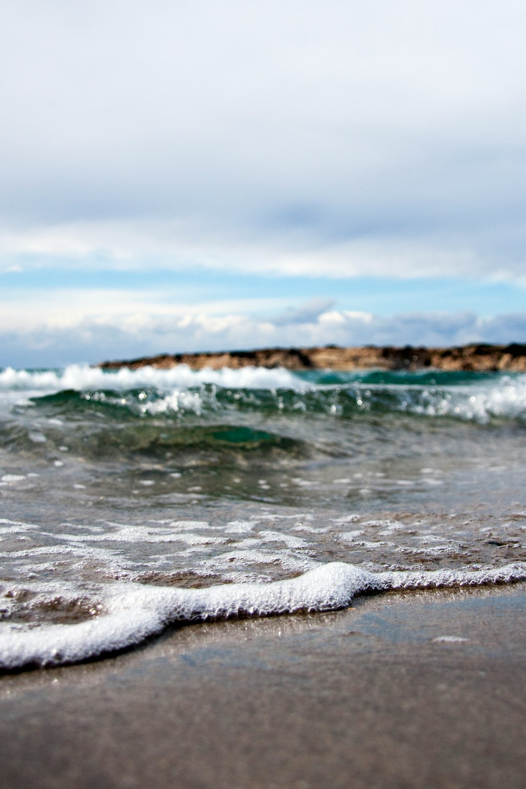 waves under white cloudy sky at daytime