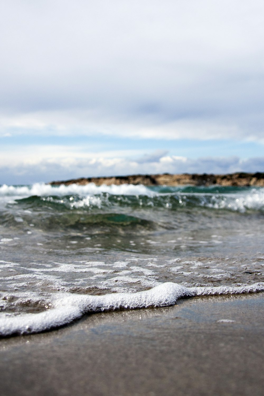 waves under white cloudy sky at daytime