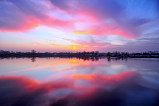 A vibrant sunset casting colorful reflections on a serene lake.