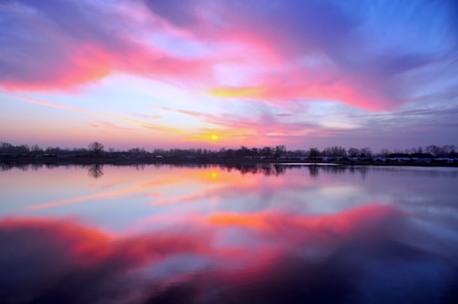 A vibrant sunset casting colorful reflections on a serene lake.
