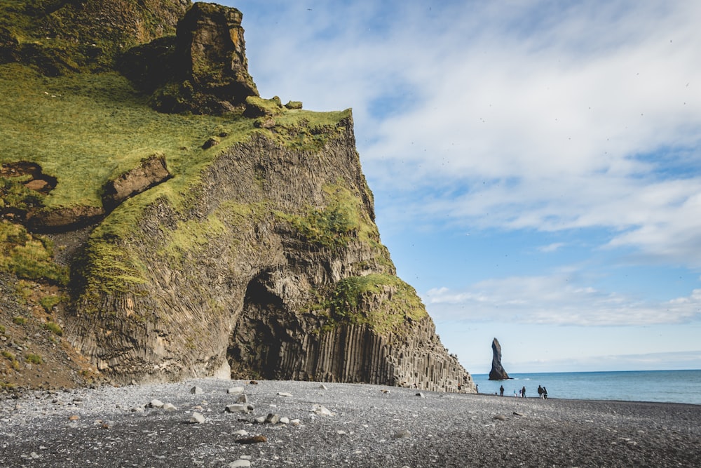 green and gray sea cliff under blue sky during daytime