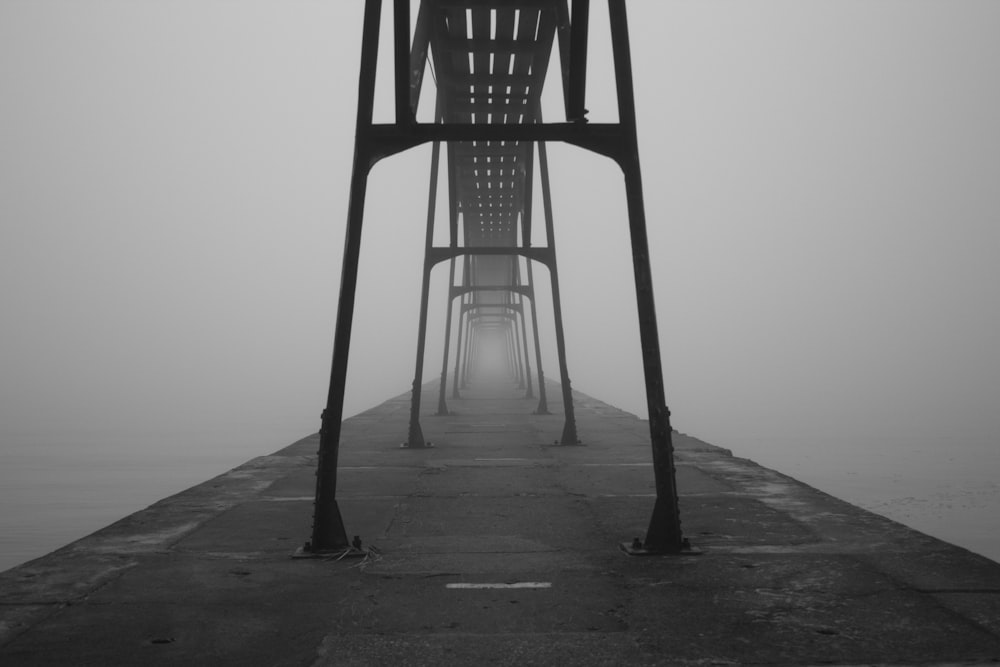 grayscale photograph of bridge between body of water