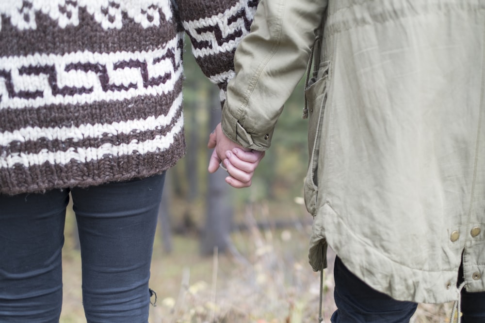 two persons holding each other's hands