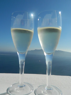 Close-up of a couple clinking glasses on the ship’s balcony, with the sparkling sea in the background.