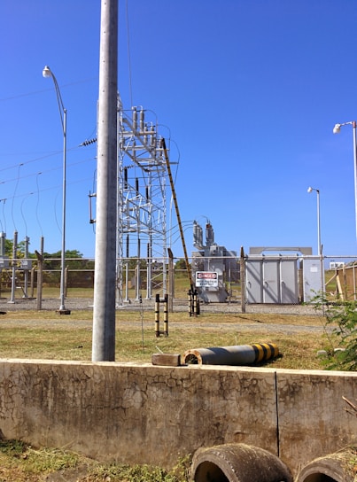 Modern high-voltage substation with engineers inspecting equipment under clear sky.