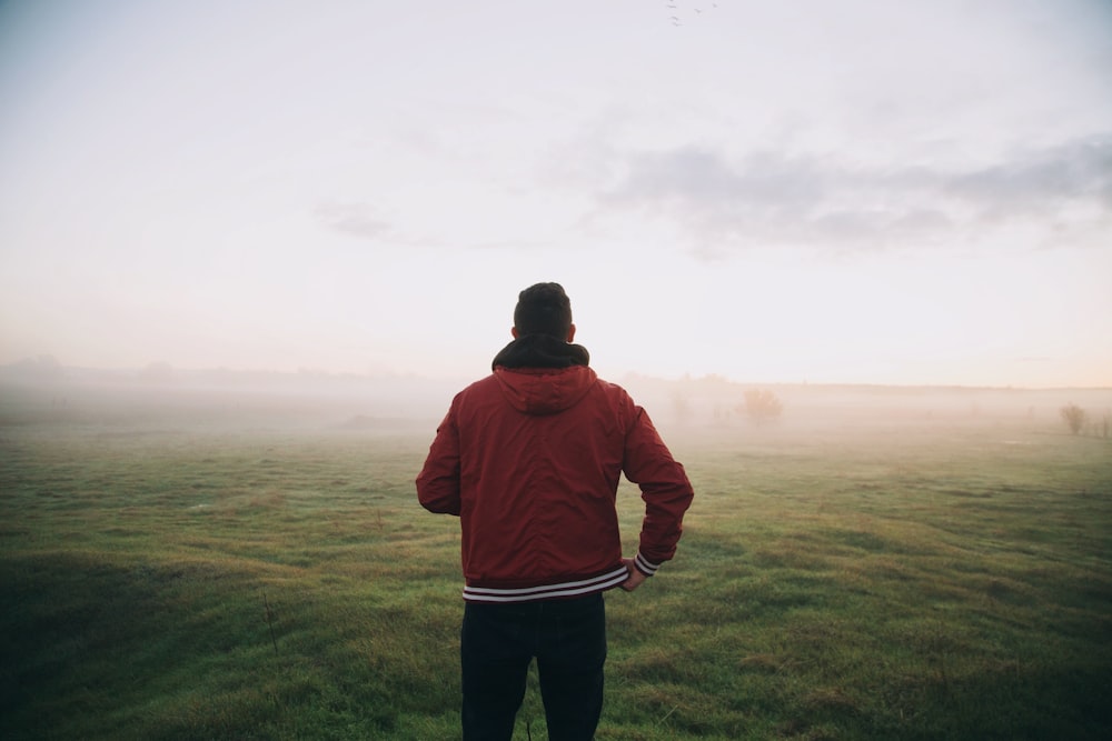 photo of man wearing red jacket facing horizon