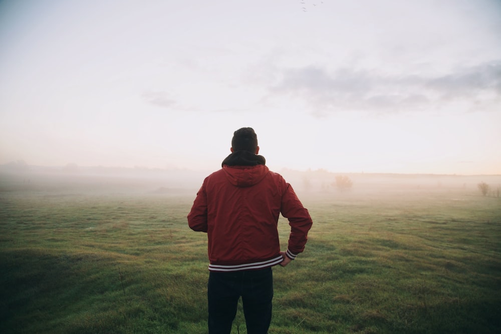 Foto eines Mannes in roter Jacke, der dem Horizont zugewandt ist