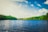 calm body of water near tall trees during daytime