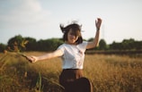 A joyful woman dancing freely in a sunlit field, embracing her confidence.