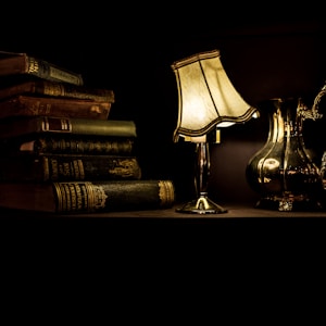 turned on desk lamp beside pile of books