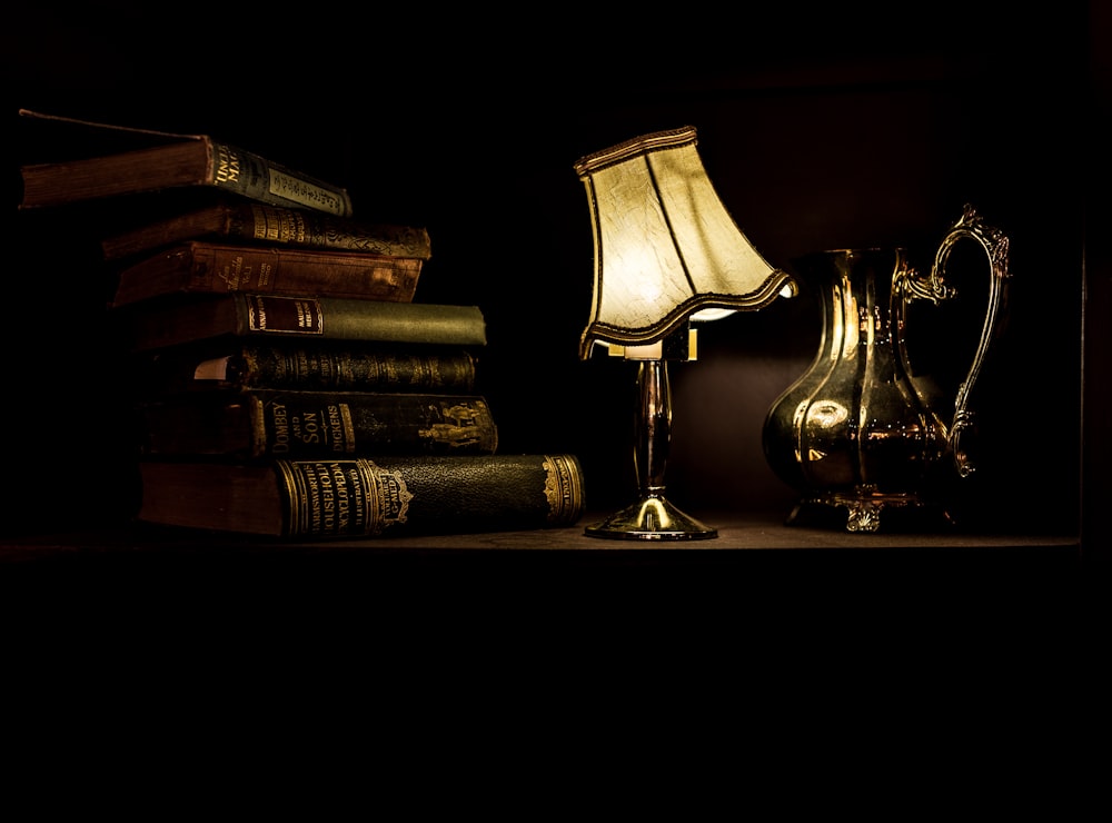 turned on desk lamp beside pile of books