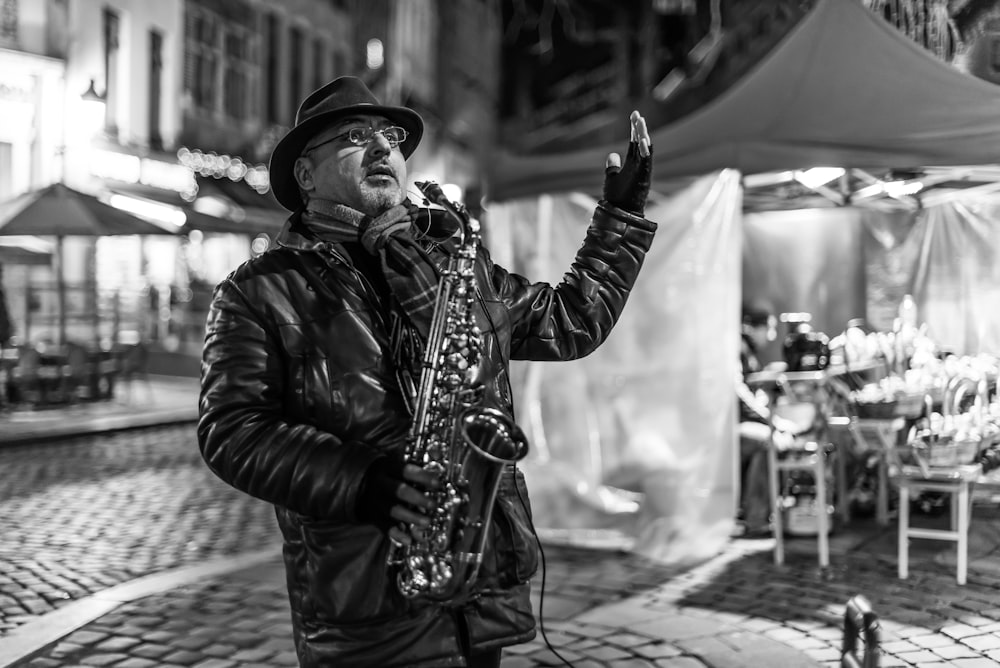 grayscale photo of man playing saxophone