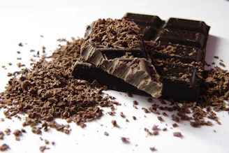 Close-up of rich, handcrafted chocolate bars with cacao beans scattered around on a rustic wooden table.