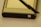 A GPS device accompanied by a stylus is positioned on a flat surface. The device has a metallic casing with a power button visible at the bottom right corner. The stylus, which appears to be black, is resting diagonally across the device.