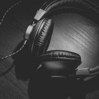 grayscale photo of corded headphones on table