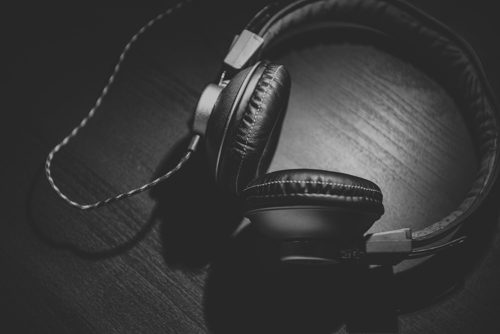 grayscale photo of corded headphones on table