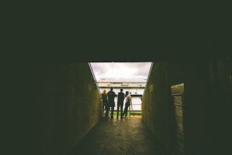four people standing near gray concrete wall during daytie