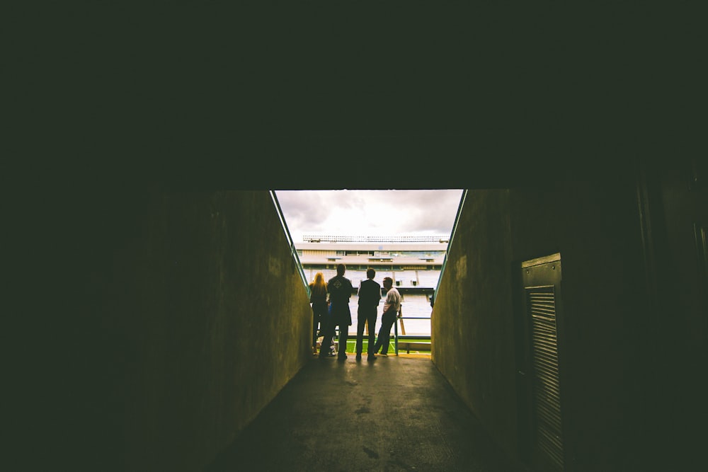 four people standing near gray concrete wall during daytie