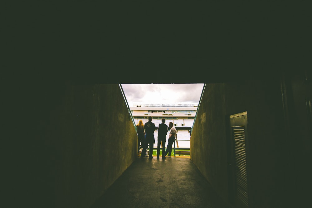 Vier Personen stehen während des Tages in der Nähe einer grauen Betonwand
