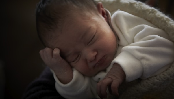 A peaceful baby sleeping in a cozy crib, surrounded by soft blankets.