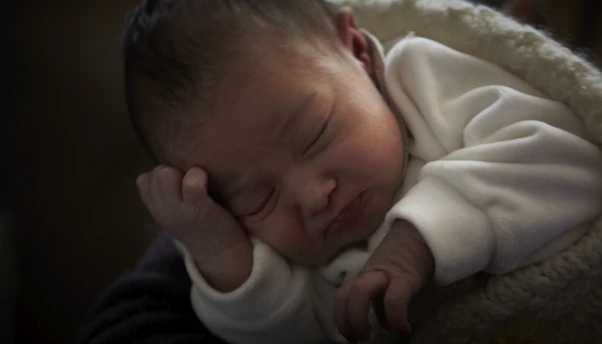 A peaceful sleeping baby wrapped in a soft blanket in a cozy nursery.