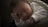 A peacefully sleeping newborn baby is nestled in a soft, fluffy blanket. The baby's face is cradled gently by its hands, giving a serene and calm impression. The baby is wearing a cozy white onesie.