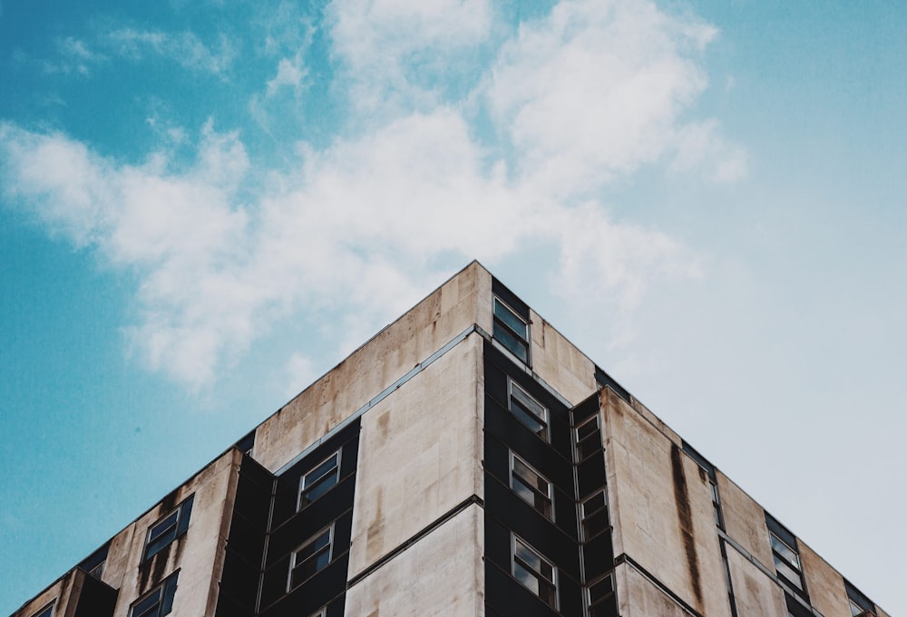 Photographie en contre-plongée d’un bâtiment en béton beige et noir sous un ciel bleu clair
