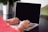 person wearing pink shirt typing on gray laptop computer on desk