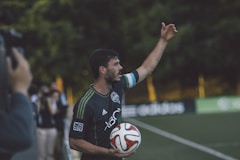 man in black and green Adidas jersey shirt holding soccer ball