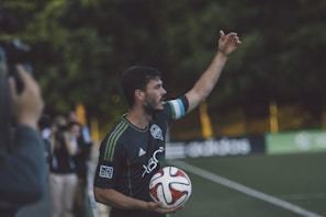 man in black and green Adidas jersey shirt holding soccer ball