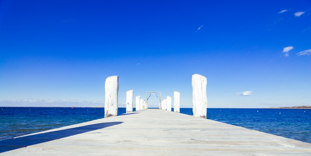 doca de madeira marrom no mar azul sob o céu azul durante o dia