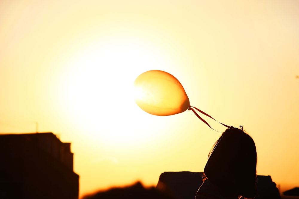 silhouette of woman holding balloon