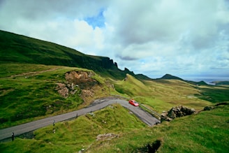 A scenic view of a winding road through lush Australian landscapes, with a family car parked nearby.
