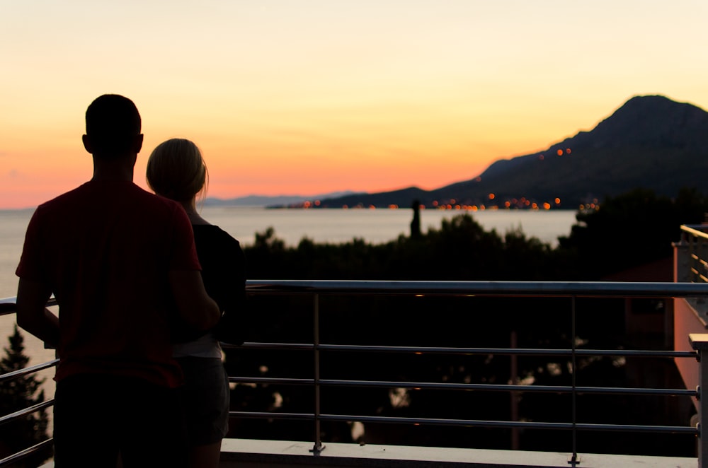 Silhouetted lovers look out over the ocean from a landing in the hills above