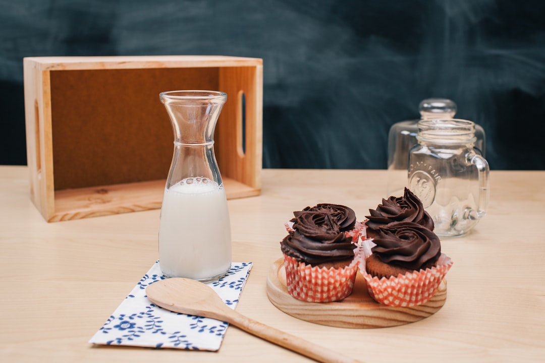 four cupcakes on brown coaster and milk jar