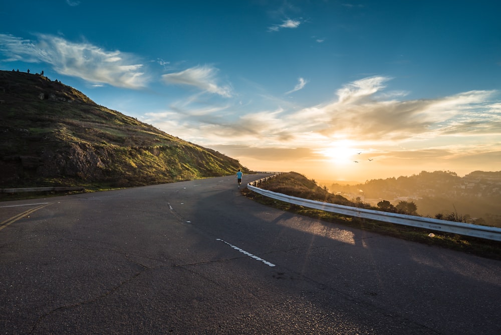 person running on road street cliff during golden hour