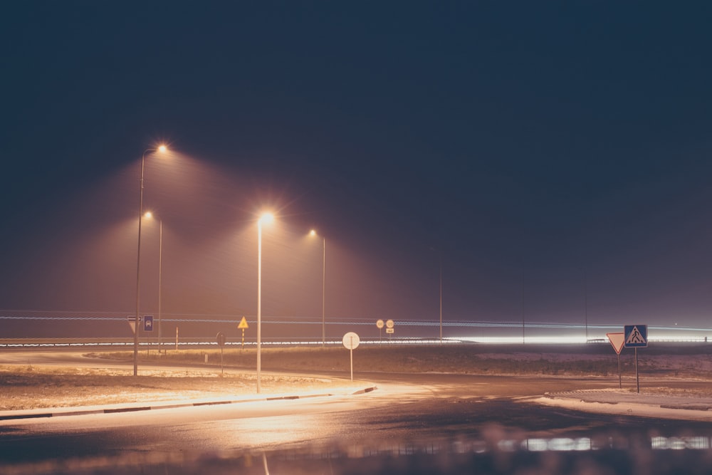 concrete road with turned on post lamp lights at nighttime