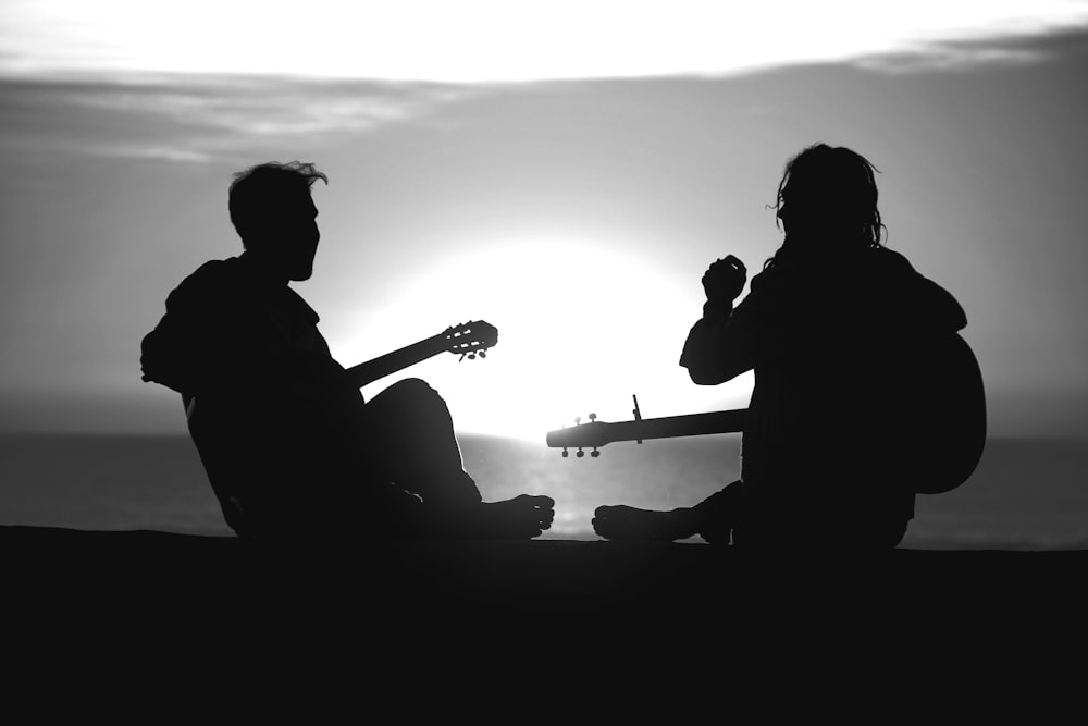 Dos figuras recortadas contra el sol, riendo con instrumentos musicales