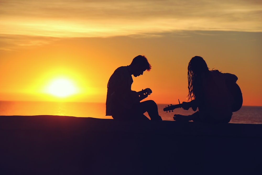 silueta de hombre y mujer tocando guitarras