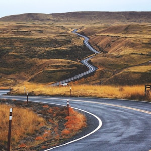 gray concrete road across brown valley during daytime