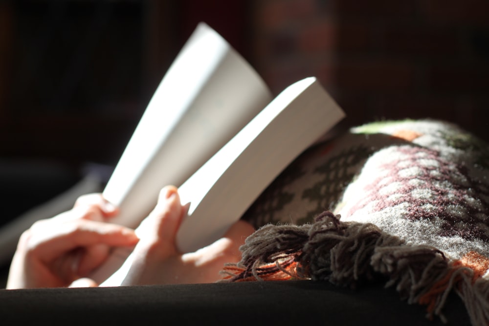 photo of person holding book near textile