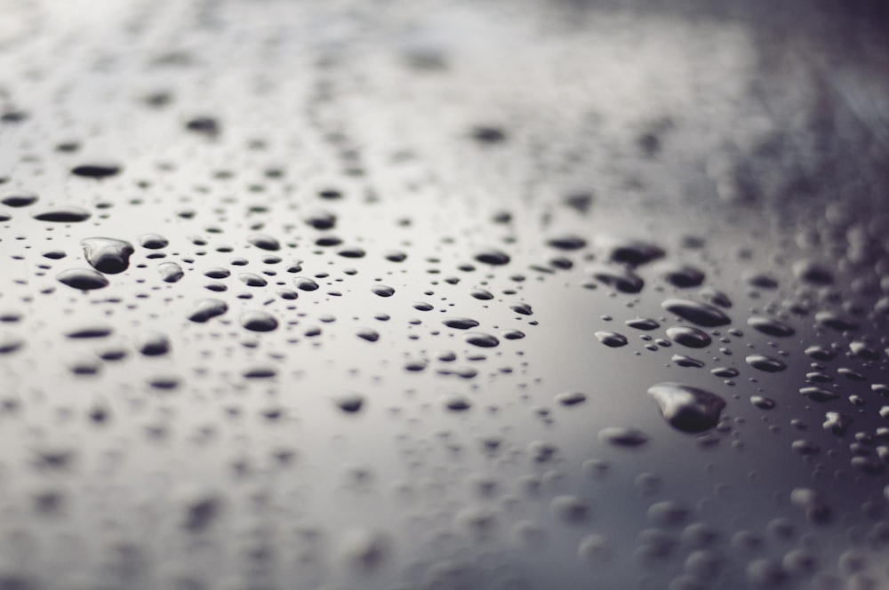 macro photography of water drops on black glass surface