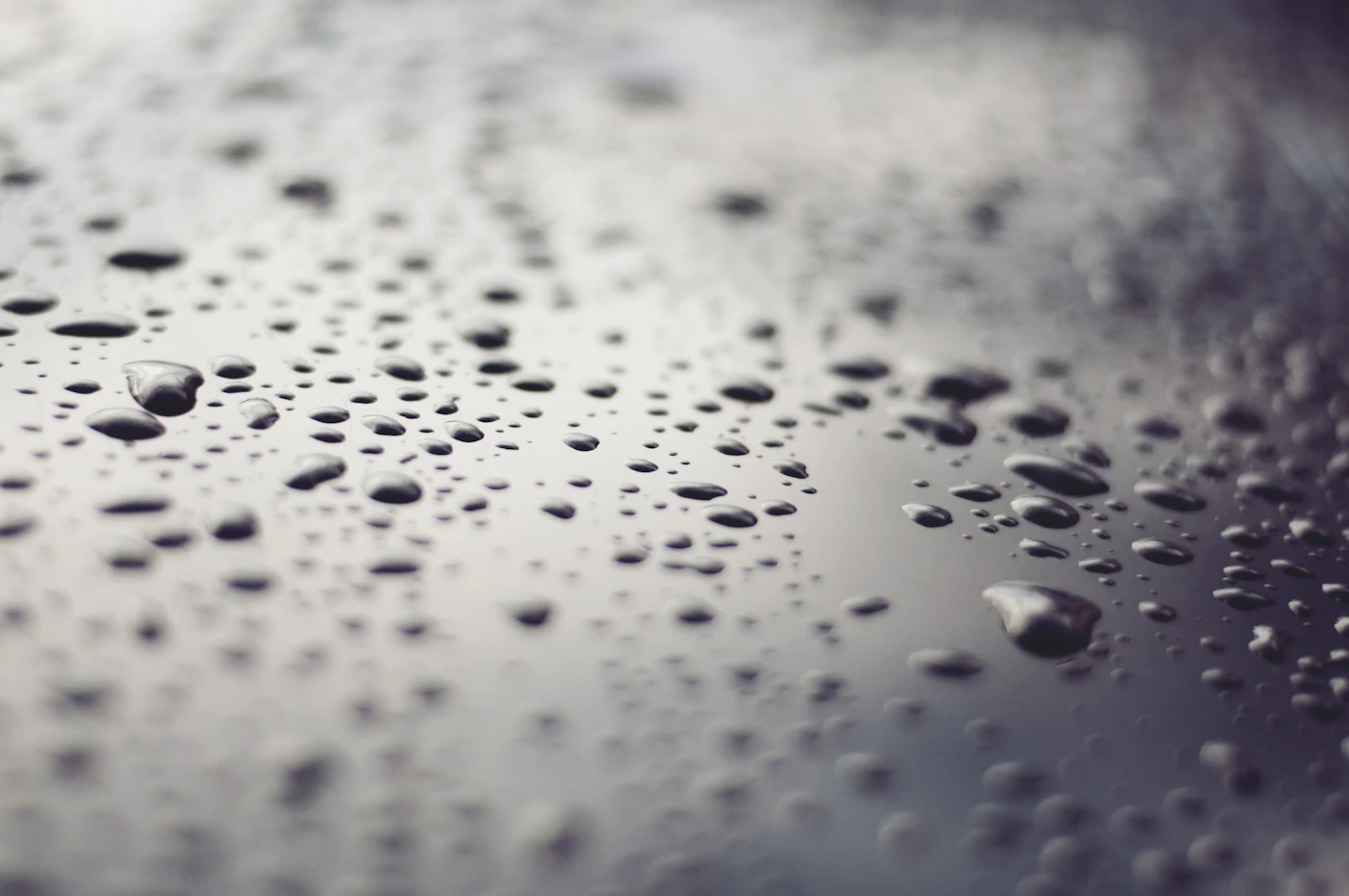 Macro photograph of water beading on a dark coated surface